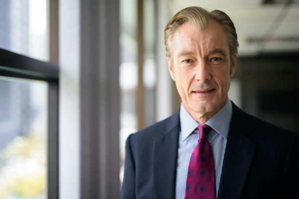 Face of happy mature handsome businessman in suit smiling by the window